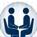 Stylized icon depicting two people facing each other across a desk, representing an interview or discussion setting.
